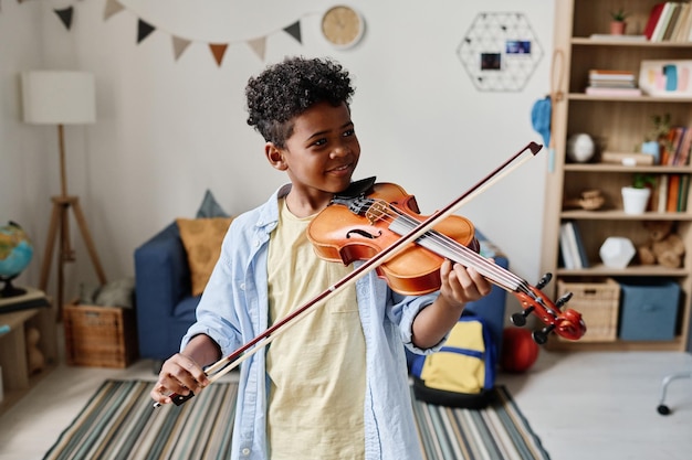 Menino africano tocando violino em casa