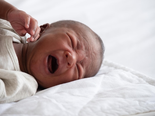 Menino afro-americano chorando em uma cama branca