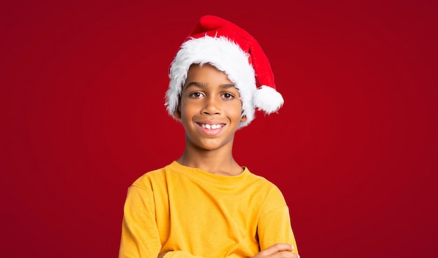 Menino afro-americano com chapéu de natal sobre fundo vermelho