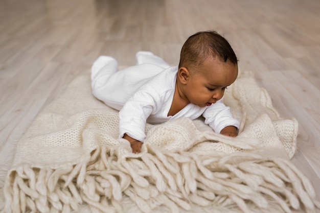 Menino afro-americano deitando-se Menino deitando-se na barriga em casa