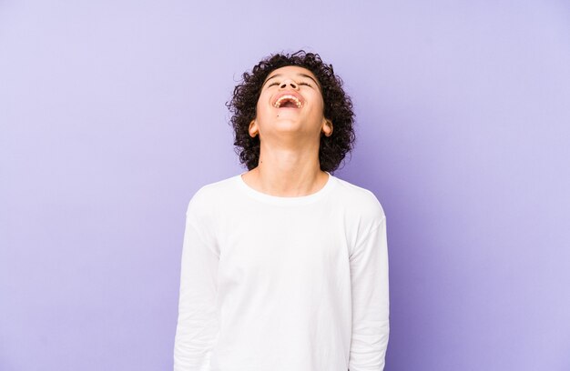 Menino afro-americano isolado relaxado e feliz rindo, pescoço esticado, mostrando os dentes.