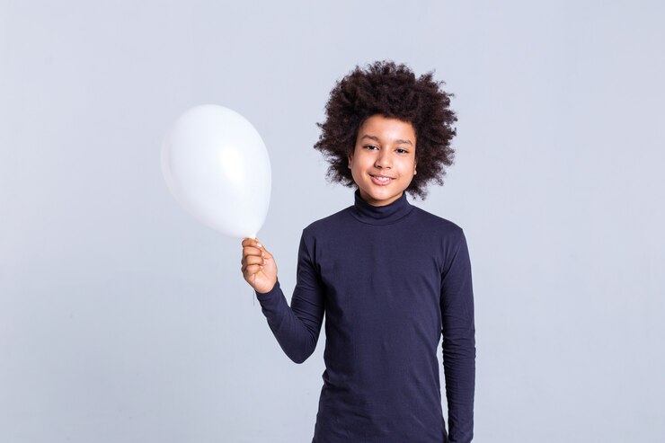 Foto menino afro-americano. menino radiante em um fundo monocromático carregando um balão de ar branco em uma das mãos