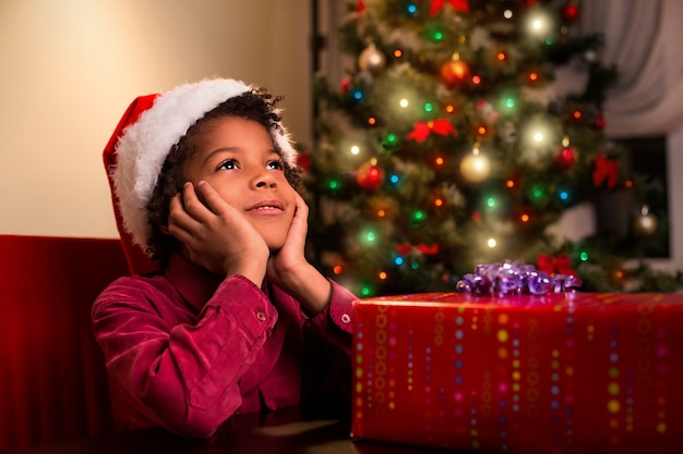 Menino afro-americano perto do presente de Natal.