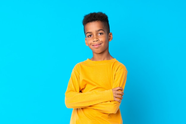 Menino afro-americano sobre azul isolado sorrindo muito