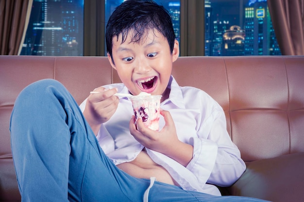 Menino alegre com excesso de peso desfrutando de sorvete gostoso