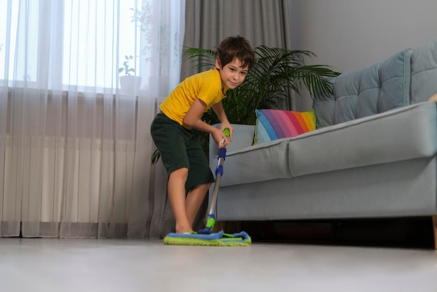 Menino alegre fica em um esfregão imaginando que ele está voando em uma casa divertida limpando o conceito de como motivar uma criança a limpar