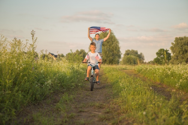 Menino andando de bicicleta em 4 de julho com o vento no campo verde