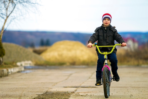 Menino andando de bicicleta no parque ao ar livre.