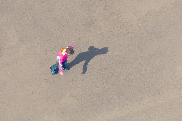 Menino andando de patins no asfalto uma vista superior