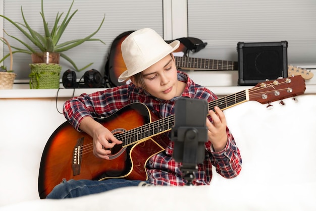 Menino aprendendo ou tirando o vlog para tocar violão por videochamada