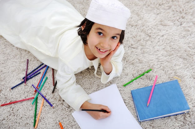Menino árabe muçulmano fazendo lição de casa em casa