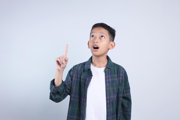 Menino asiático apontando para cima mostrando espaço de cópia para publicidade