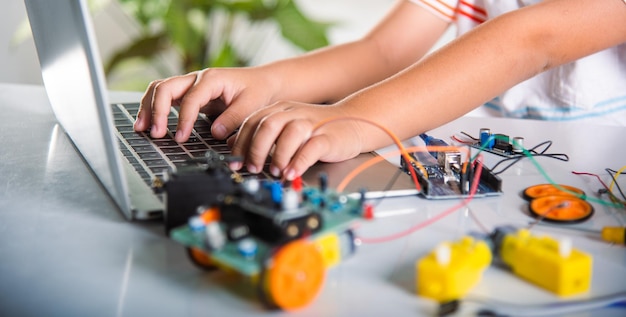 Menino asiático aprende codificação e programação com laptop para carro robô Arduino