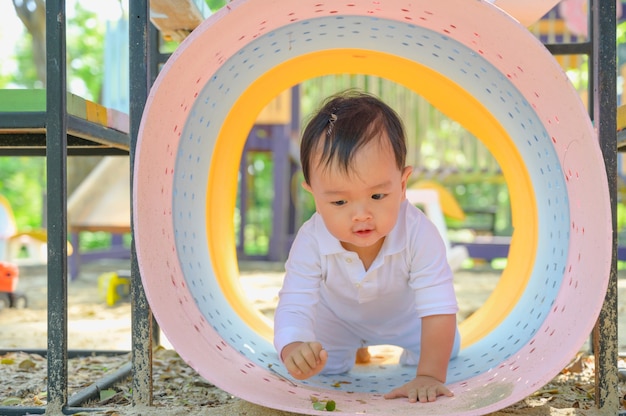 Menino asiático brincando com areia em uma caixa de areia. Bebê saudável e ativo ao ar livre brincando