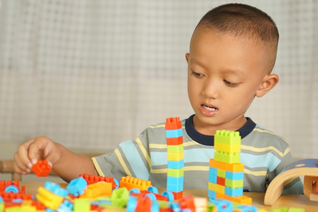 Foto menino asiático brincando com brinquedos educativos há muitas cores lindas na mesa da casa