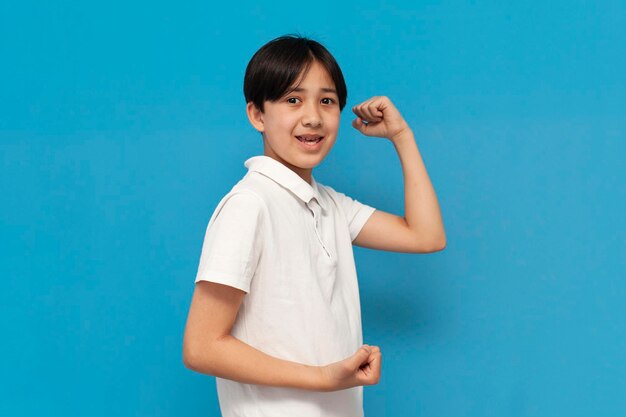 menino asiático de doze anos se alegra com a vitória sobre o fundo azul isolado vencedor criança coreana