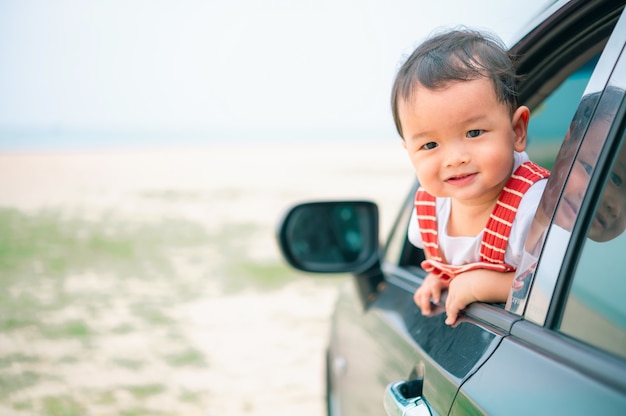 Menino asiático espia para fora do carro.