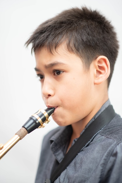 Foto menino asiático músico tocando saxofone