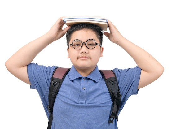 Menino asiático obeso inteligente usando óculos e segurando uma pilha de livros na cabeça