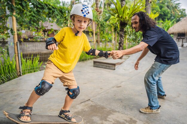 Menino atlético aprende a andar de skate com um treinador em um parque de skate Esportes de educação infantil