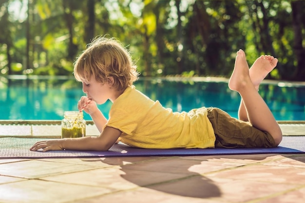 Menino bebendo smoothie verde deitado na piscina