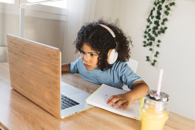 Menino bebendo suco enquanto joga no computador