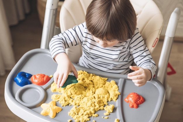 Menino bonitinho brincando com areia cinética Desenvolvimento de habilidades motoras finas Educação sensorial precoce Atividades Montessori Sensoriais em casa