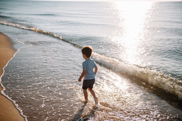 Menino bonitinho brincando na praia