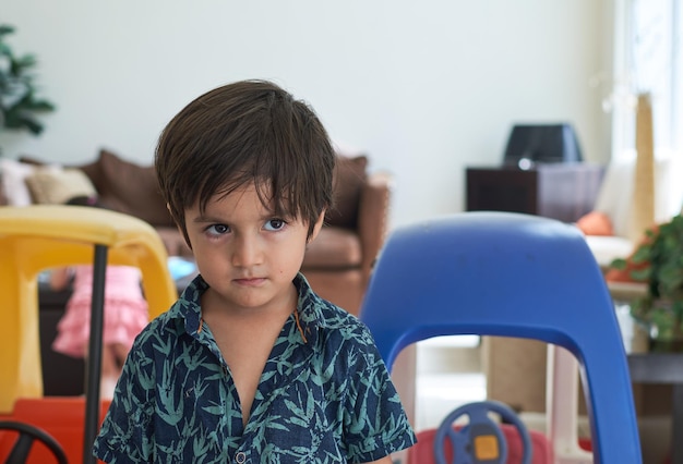 Menino bonitinho com cara de bravo no fundo de carros de brinquedo coloridos