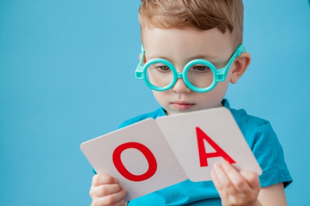 Menino bonitinho com carta no fundo. criança aprende letras. alfabeto