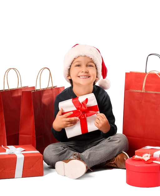 Menino bonitinho com chapéu de papai noel, com caixas de presente e sacolas de compras isoladas