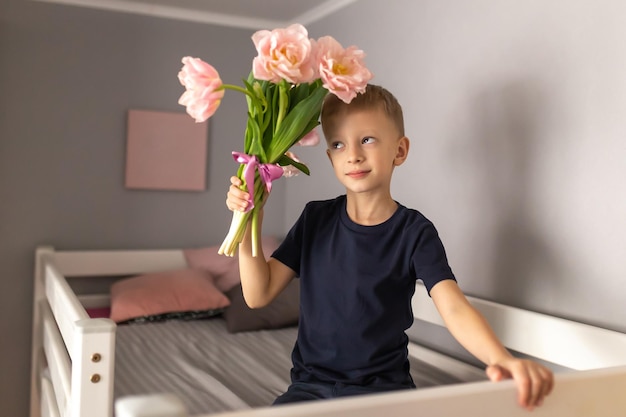 Menino bonitinho com um buquê de flores Tulipas Dia das Mães Dia Internacional da Mulher