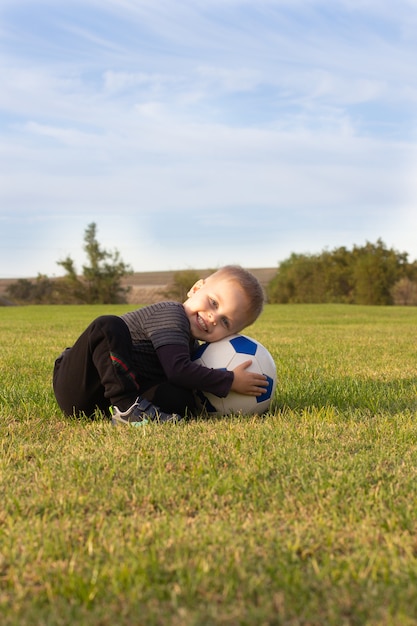 Menino bonitinho com uma bola no belo parque na natureza