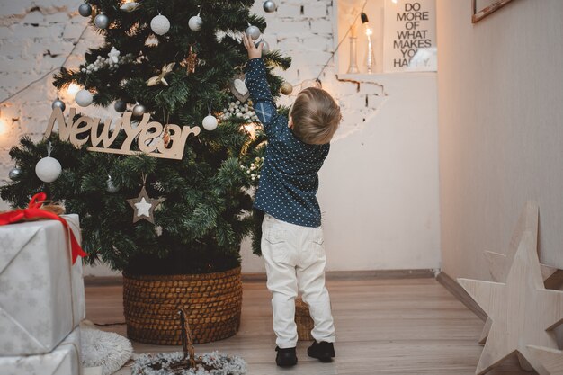 Menino bonitinho decorando a árvore de natal