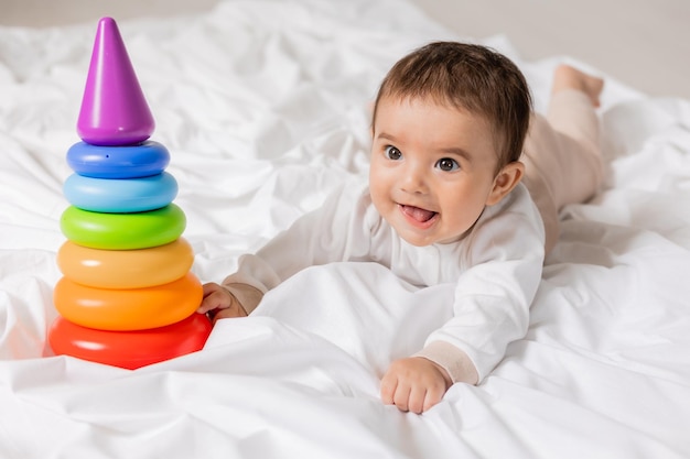 menino bonitinho deitado no cobertor e brincando com saúde de banner de cartão de brinquedo pirâmide colorida