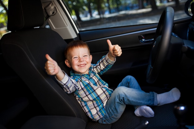 Menino bonitinho dirigindo carro de pais