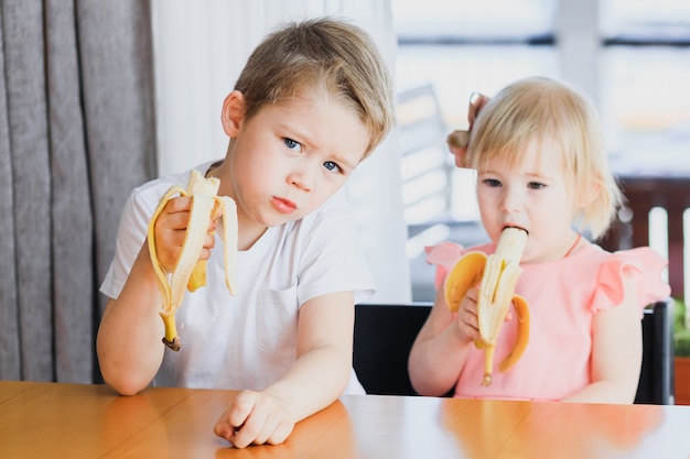 Menino bonitinho e menina comendo banana