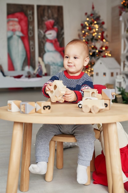 Menino bonitinho está brincando com o trem de brinquedo de madeira, carro de brinquedo, pirâmide e cubos, aprendendo o conceito de desenvolvimento. Desenvolvimento de habilidades motoras finas para crianças, imaginação e pensamento lógico