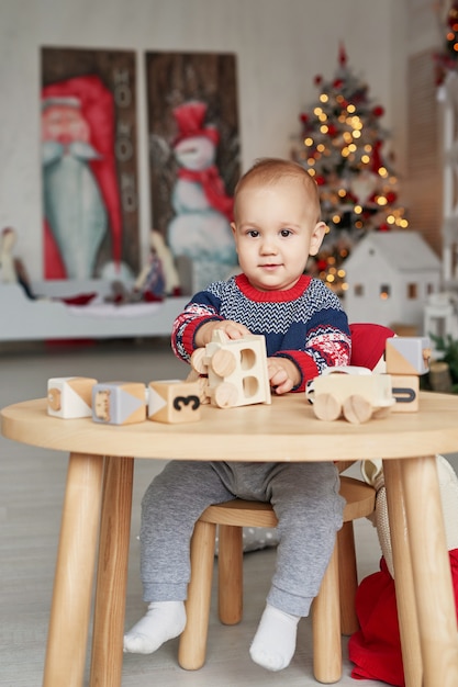 Menino bonitinho está brincando com o trem de brinquedo de madeira, carro de brinquedo, pirâmide e cubos, aprendendo o conceito de desenvolvimento. Desenvolvimento de habilidades motoras finas para crianças, imaginação e pensamento lógico