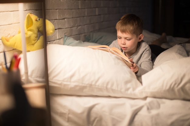 Menino bonitinho lendo livro à noite