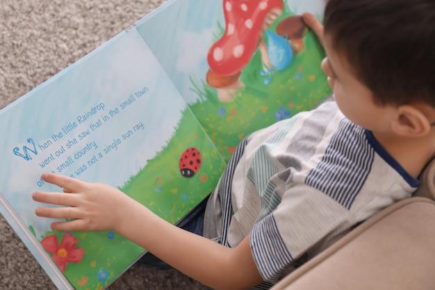 Menino bonitinho lendo livro em casa