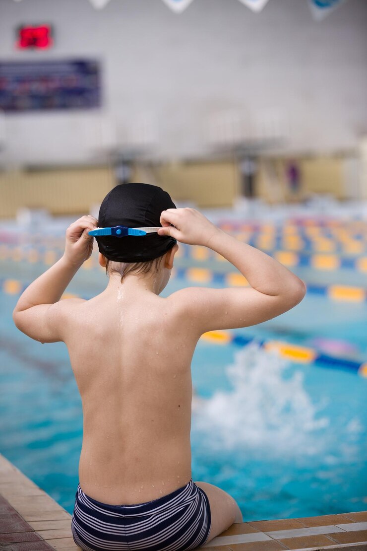 Menino bonitinho pronto para mergulhar na piscina esportivaAtividades esportivas internas para criançasTreinamento para competição