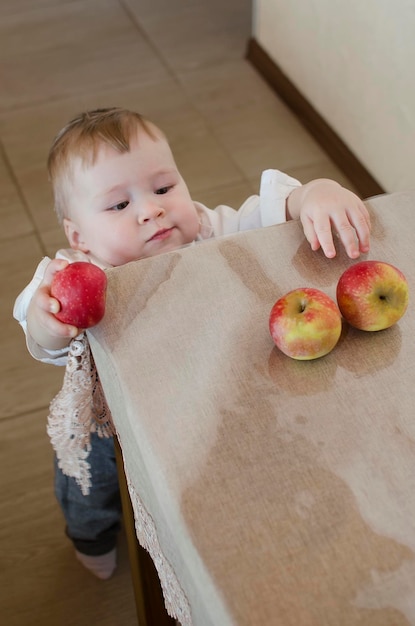 Menino bonitinho quer comer uma maçã da mesa