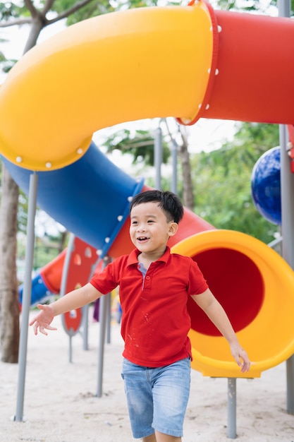 Menino bonitinho se divertindo em um playground ao ar livre no verão