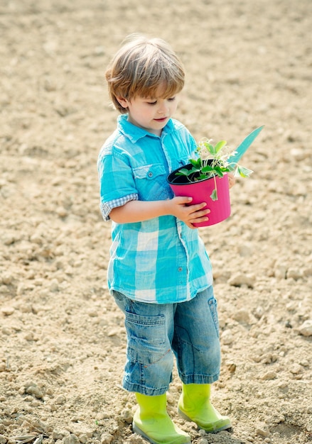 Menino bonitinho se divertindo no campo infantil agricultor trabalhando no campo filho do conceito de infância feliz