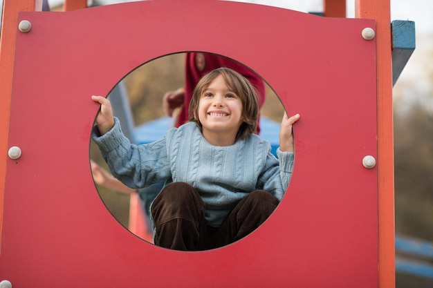 menino bonitinho se divertindo no parque infantil no dia cludy autum