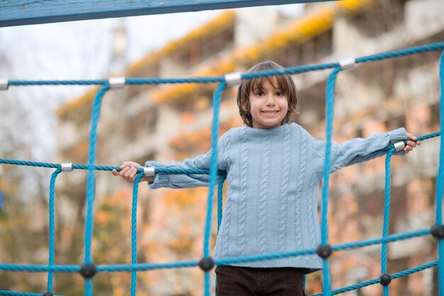 menino bonitinho se divertindo no parque infantil no dia cludy autum