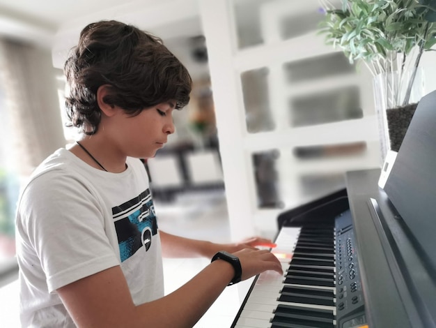 Menino bonitinho vestido de maneira elegante tocando piano de concerto