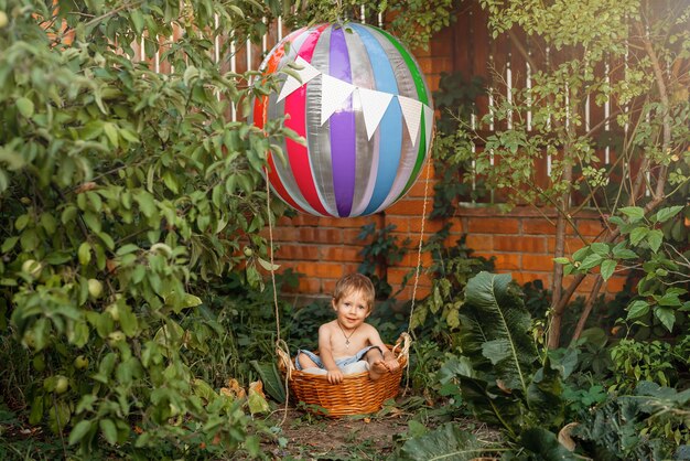 Menino bonito andando de balão de ar quente se divertindo voando