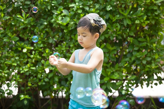 Menino bonito brincando com bolhas